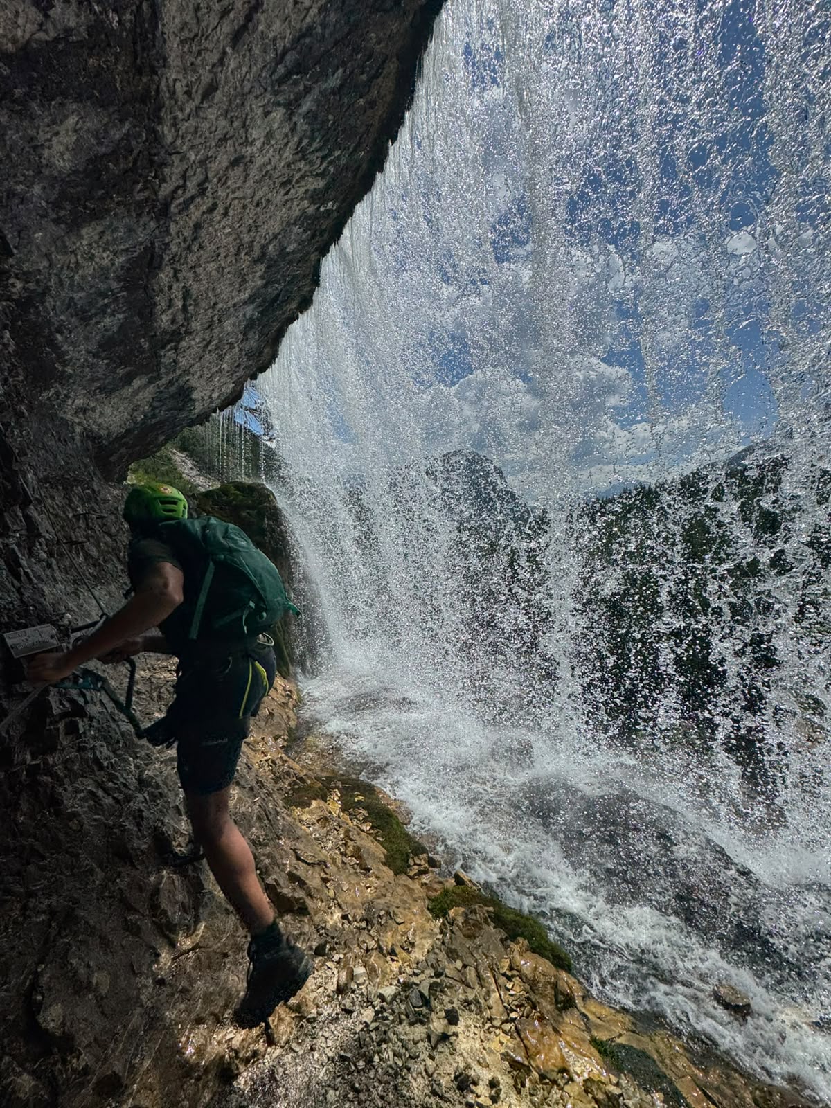 Hiker on a via ferrata behind a waterfall in the Dolomites