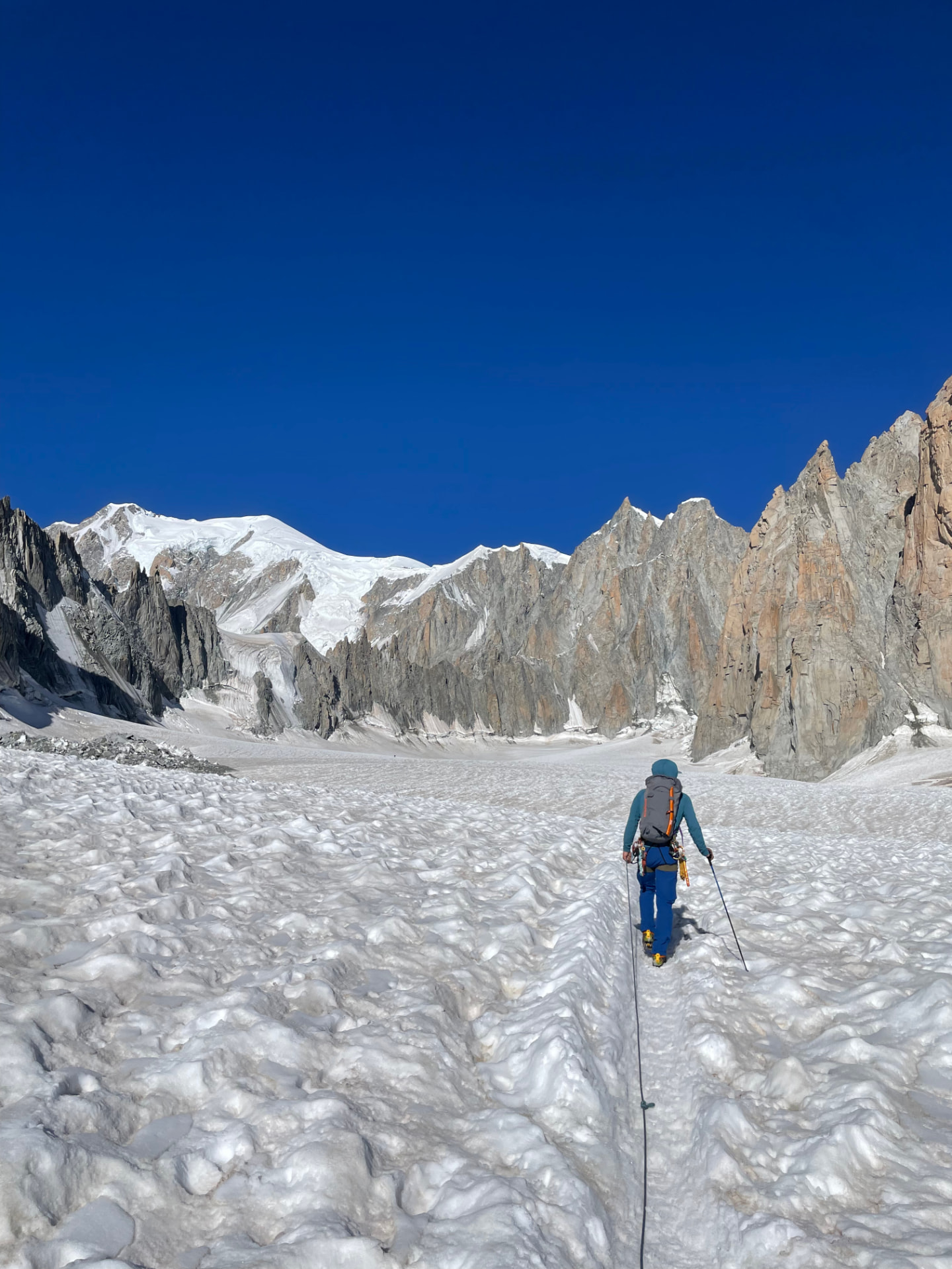 Roped mountaineer crossing a glacier towards granite spires