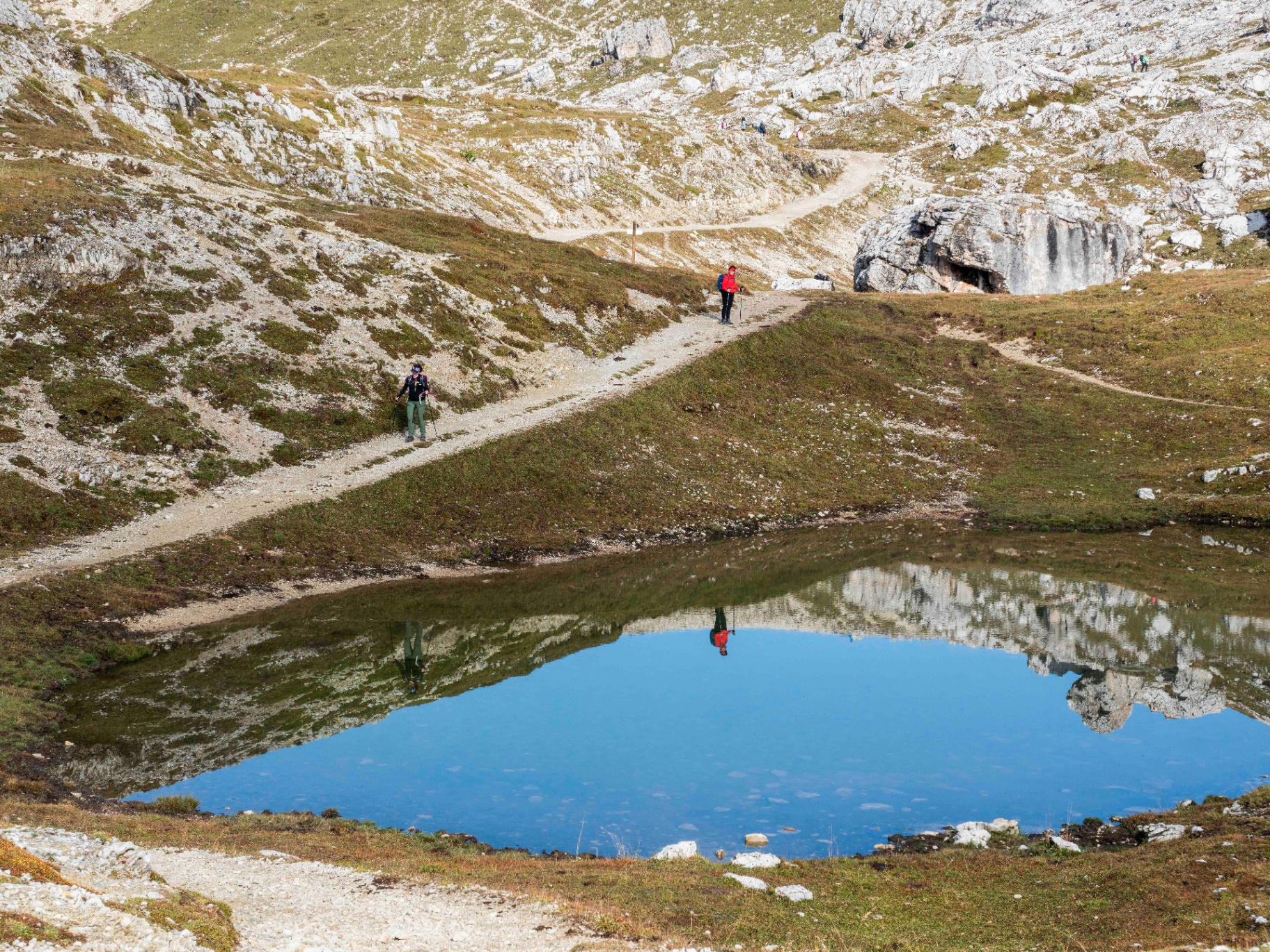 Escursionisti su sentiero con laghetto alpino Dolomiti